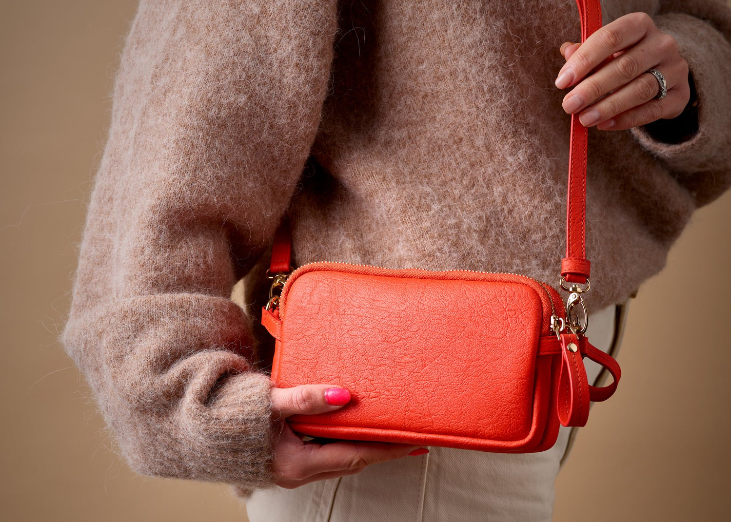 Person holding a Tanya Rose Flossy Crossbody Double Zip Coral Handbag with Navy Lining