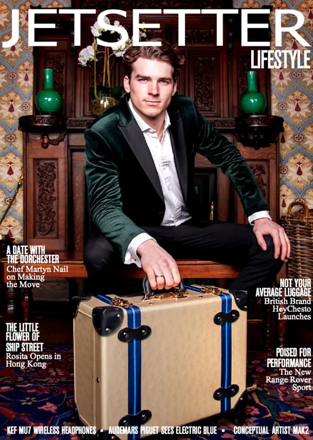 Man in green velvet blazer holding vintage-style suitcase with blue stripes, featured on Jetsetter Lifestyle magazine cover